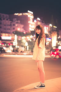 Woman in White Shirt Standing on Roadside during Night Time thumbnail