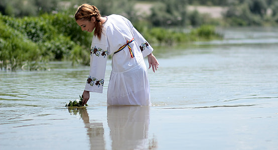 woman on lake holding a green plant thumbnail