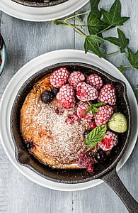 baked bread with fruits on black steel cook pan beside green leaf plant thumbnail