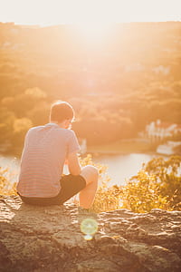 man sitting on gray rock sepia photo thumbnail