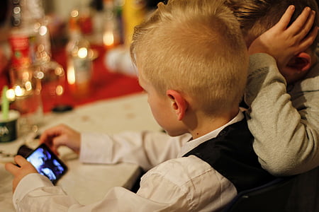 focus photo of boy holding phone near table with bottles thumbnail