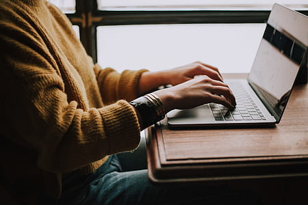 person in brown knitted sweater using laptop during daytime thumbnail