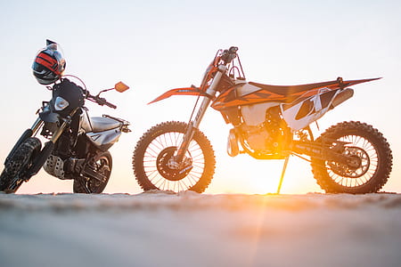two parked black and orange dual-sport motorcycles thumbnail