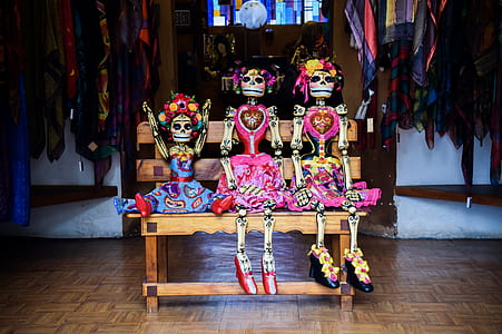 three sugar skulls sitting on brown wooden bench thumbnail