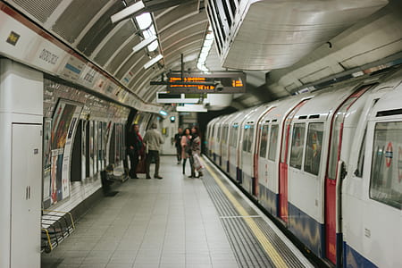 people in train station near white train thumbnail