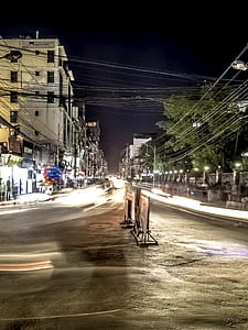 timelapse photography of vehicles on road near building and trees thumbnail