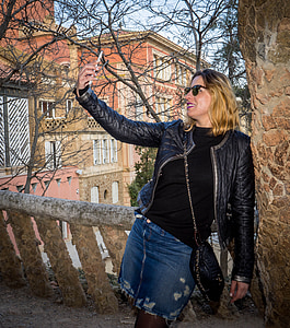 woman in black leather jacket leaning on wall during daytime thumbnail