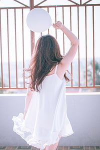 woman in white sleeveless dress holding balloon thumbnail