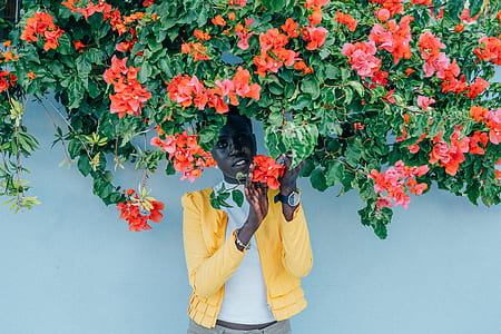 woman wearing yellow cardigan while touching orange petaled flower thumbnail