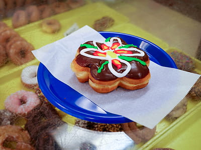 Flower donut sitting on a blue plate in a donut shop. thumbnail