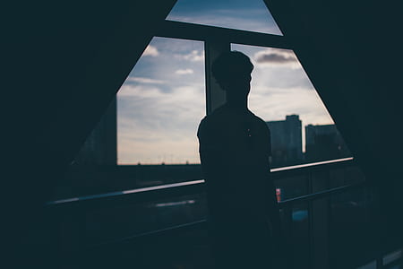 person leaning on metal rail near window thumbnail