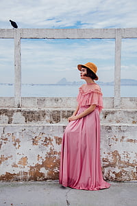 woman in pink dress standing beside wall during daytime thumbnail