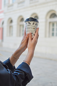 person holding white and black disposable cup with black lid thumbnail
