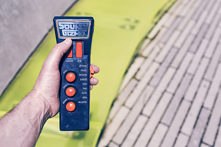 person holding black and orange Sound Gizmo remote control thumbnail