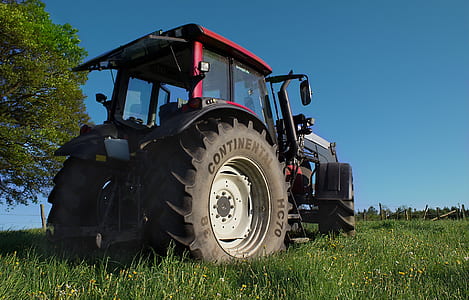 red and black tractor parked on green grass at daytime thumbnail