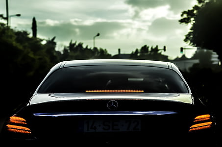 black Mercedes-Benz vehicle near green trees thumbnail