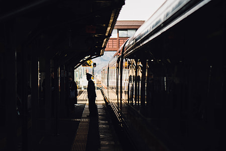 man standing on train station near train thumbnail