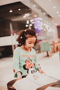 toddler wearing green and orange Minnie Mouse crew-neck shirt sitting down at table thumbnail