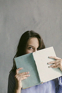 Woman in Blue Striped Flannel Shirt Holding a Book Indoors thumbnail