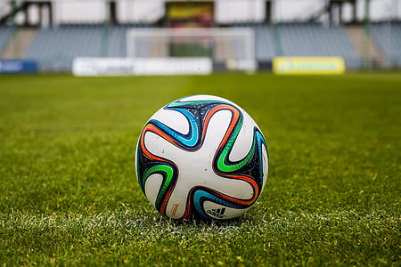 white, blue, and green adidas soccer ball on grass field thumbnail