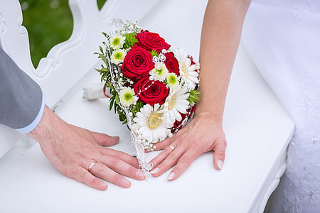 red rose, white daisies, and green mums flower bouquet beside man and woman hands thumbnail