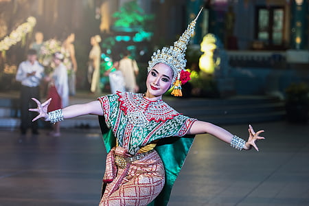 woman in green and red dress dancing near two talking peopel thumbnail