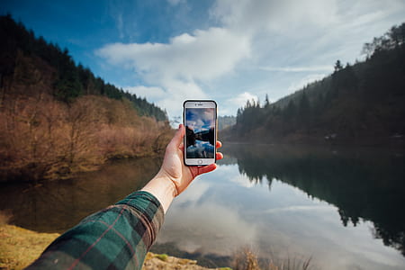 person taking photo of landscape using iPhone thumbnail