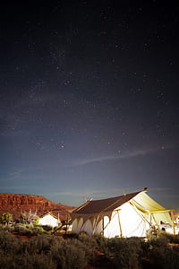 lighted white tents in front of brown rock formations thumbnail