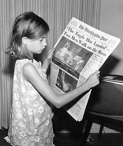 girl holding newspaper near window curtain thumbnail
