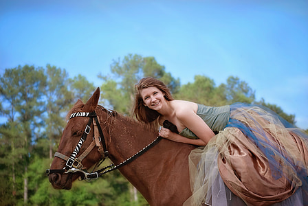 woman in green and brown dress riding horse thumbnail