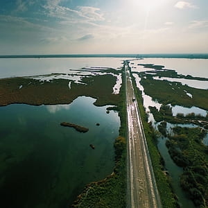 brown road in the middle of body of water at daytime thumbnail