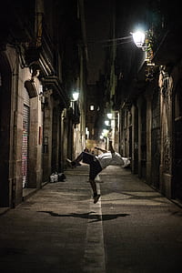 photo of person doing back flip in the middle of pathway during nighttime thumbnail