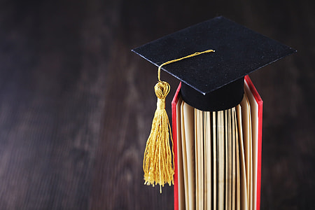 black and yellow graduation hat in red book thumbnail