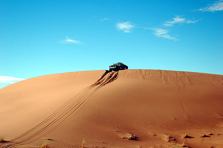 vehicle on cliff under blue sky thumbnail