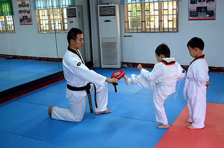 man wearing karate gi teaching child to kick inside training room thumbnail