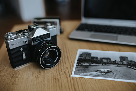 Old Zenit camera and a Canon camera with black-and-white photos on a wooden table thumbnail