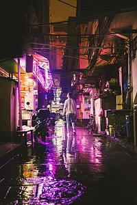 man standing in alley looking at neon signage thumbnail