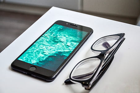 black iPhone 7 and black framed clear lens sunglasses thumbnail