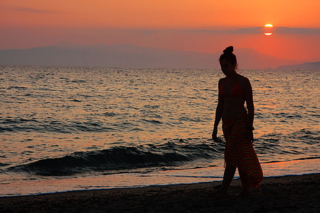 silhouette of woman walking near on seashore during golden house thumbnail