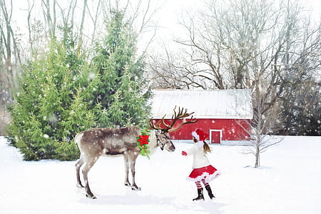 girl with white and red Santa costume on snow hugging reindeer thumbnail