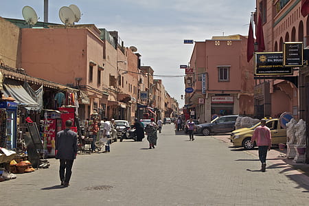 group of people walking on road in between buildings during daytime thumbnail