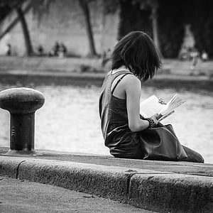 woman sitting on pavement reading book thumbnail
