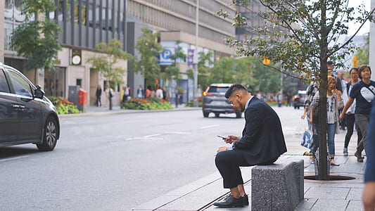 person wearing black suit jacket sitting on gray concrete bench thumbnail