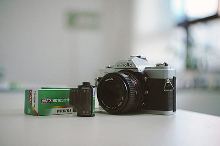 selective focus photo of black and gray Minolta DSLR camera beside battery and Fujifilm box thumbnail
