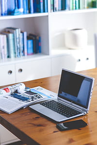 grey Acer laptop on brown wooden table beside magazine and smartphone thumbnail