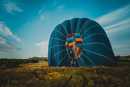 blue hot air balloon landed on grass field thumbnail