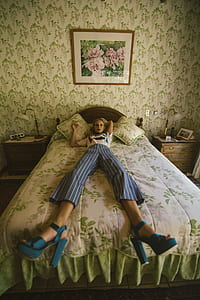 Woman in White Shirt Lying on White and Green Bed thumbnail