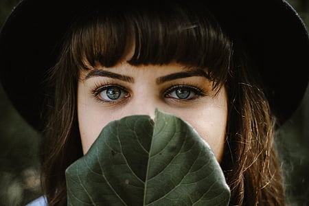 woman covering her mouth with green leaf thumbnail
