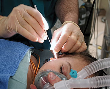 person holding metal tool check up girl's ear thumbnail