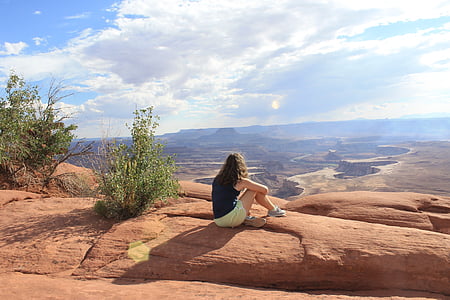 woman sits on brown mountain peak during daytime thumbnail